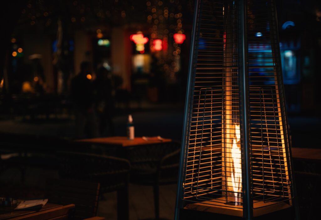 Estufa de gas exterior en terraza de hostelería proporcionando calor en espacios al aire libre durante la noche