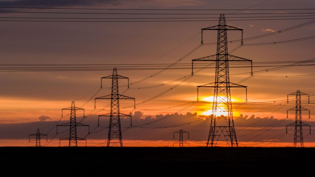 imagen de una puesrta de sol com cuadros eléctricos de fondo representando el sistema eléctrico español y el SRAD